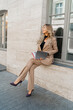 © Svetlana Sokolova - Business woman in stylish beige suit  holdig advertising catalogs and posing outdoor.