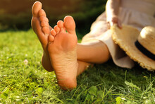 Woman Sitting Barefoot On Green Grass Outdoors, Closeup