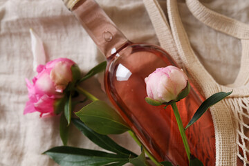 Sticker - Rose wine and beautiful peonies in mesh bag on white fabric, closeup