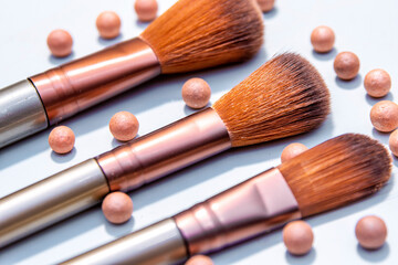 Cosmetic powder balls and makeup brush isolated on white background.