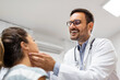 © Graphicroyalty - medicine, healthcare and medical exam concept - doctor checking patient's tonsils at hospital. Endocrinologist examining throat of young woman in clinic