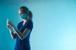 © PoppyPix - young lady nurse with a protective mask holiding a vaccination syringe - light blue background closeup. High quality photo
