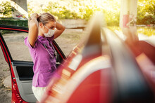 A Young Nurse Prepares For Her Shift At Work. A Nurse Dressed In Her Uniform Standing Outdoors In Front Of Her Car With A Mask On Her Face During The Day.