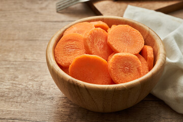 chop round carrot on a wooden bowl on wood table background                                