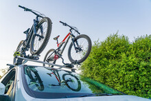 Looking Up At Two Mountain Bikes On The Roof Racks Of A Car With A Reflection In The Windscreen