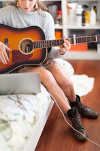 Girl Playing Guitar In Her Bedroom