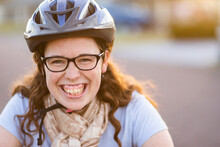 Smiling Portrait Of A Young Lady In Her Twenties Riding With A Bike Helmet On