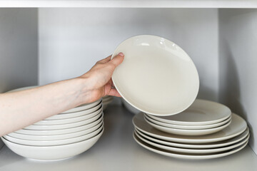 Wall Mural - Person's hand stacking white ceramic plates after washing