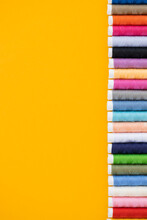 Different Colorful Sewing Threads On Yellow Background, Flat Lay