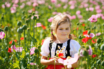 Wall Mural - Little preschool girl in poppy field. Cute happy child in red riding hood dress play outdoor on blossom flowering meadow with pink poppies. Leisure activity in nature with children.