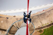 © chitsanupong - Focus top view male worker down height tank roof rope access safety inspection of thickness storage tank gas