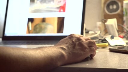 A man watches content on a computer screen. Laptop on the table. Receiving the information. Photo and video content.. Surfing on the Internet. Tester. User. IT-specialist. Close-up.