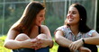 © Marco - Candid female friends in conversation outside at park. Two girlfriends speaking to each other smiling and laughing