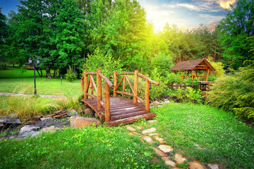 Wall Mural - wooden bridge over stream in green garden