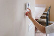 © Amy Covington/Stocksy - Woman changing a thermostat