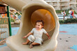 © Erin Brant/Stocksy - Joyful young girl with limb difference on slide