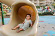 © Erin Brant/Stocksy - Happy young girl with limb difference on slide
