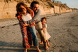 © Erin Brant/Stocksy - Happy parents and girl hugging on beach