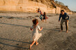© Erin Brant/Stocksy - Joyful parents and girls playing on beach