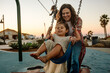 © Erin Brant/Stocksy - Happy mom pushing barefoot girl on swing