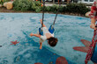 © Erin Brant/Stocksy - Young girl swinging face down at playground