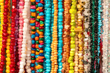 Colorful Beads Threads Made Of Natural Semiprecious Stones Background. Isolated Jewelry Close Up. Stone Texture, Energy Mineral, Beaded Necklaces, Rock. Selective Focus