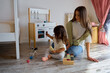 © Tatiana Timofeeva/Stocksy - mom and daughter play with toy kitchen