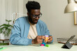 © Valentina Barreto/Stocksy - Black man making wooden geometric puzzle at work