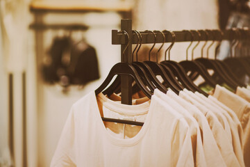 White cotton casual T-shirts hang on black hangers in a clothing store. Shopping and sale. Different sizes of clothes. Fashion.