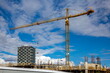 New construction of high-rise buildings in Burnaby city, industrial construction site, construction equipment, construction crane on the background of finished skyscrapers and a blue cloudy sky