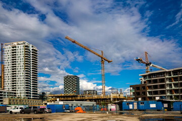 Wall Mural - New construction of high-rise buildings in Burnaby city, industrial construction site, construction equipment,  construction crane on the background of finished skyscrapers and a  blue cloudy sky