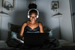 © Ezequiel Giménez/Stocksy - Happy young black female using laptop at night