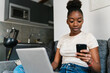 © Ezequiel Giménez/Stocksy - Young black female with laptop using smartphone