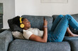 © Ezequiel Giménez/Stocksy - Black teen meloman browsing social media on sofa
