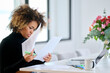 © Guille Faingold/Stocksy - Black female freelancer reading papers