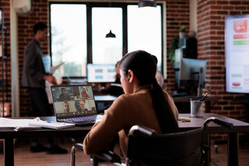 Wall Mural - Woman with chronic impairment attending videocall meeting in disability friendly office, chatting with people on online videoconference. Wheelchair user talking on remote teleconference.