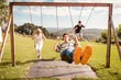 © Ibai Acevedo/Stocksy - Family having fun on the swings at the park