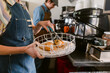 © ByLorena/Stocksy - Crop barmaid with empanadas on tray at coffee shop