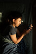 © Alison Winterroth/Stocksy - A girl looks at her screen in the golden hour.