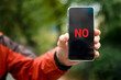 NO on the smartphone screen. A smartphone with the word NO on the smartphone screen in a man's hand. Message using a mobile phone or modern technology. Close-up. Copy Space