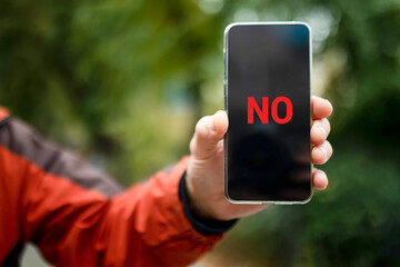 no on the smartphone screen. a smartphone with the word no on the smartphone screen in a man's hand.