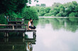 © Balazs Kovacs/Stocksy - woman sitting on a pier by a lake