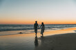 © David Prado/Stocksy - Loving couple holding hands on beach at sunset
