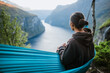 © Alina Miluseva/Stocksy - Man resting in hammock and watching Norwegian landscape