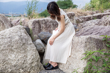 Wall Mural - 岩場に腰掛ける女性　Woman sitting on a rock