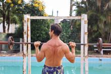 Strong Man Seen From Behind Working Out With A Rusty Dumbbell By Pool 