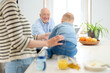 © Guille Faingold/Stocksy - Baby on kitchen counter crawling to granddad.