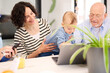 © Guille Faingold/Stocksy - Happy family with baby using laptop at home.