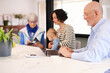 © Guille Faingold/Stocksy - Grandfather working on laptop beside his family.