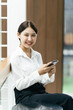 © PaeGAG - Asian businesswoman in formal suit in office happy and cheerful during using smartphone and working.